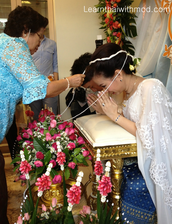 The bride's grandmother is putting the Mong Kol for the couple.